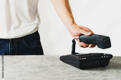Man holds handset near concrete table with old telephone on white background. Communication concept. Copy space