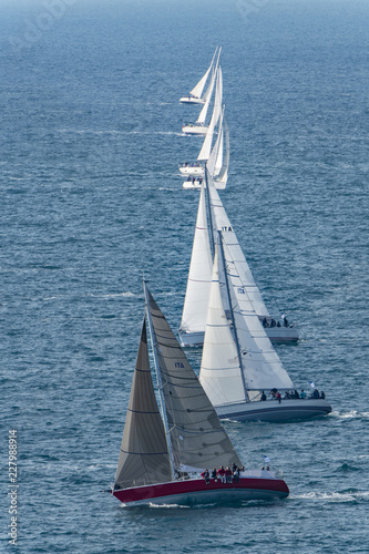 Barche a vela in competizione durante una regata, con vento forte