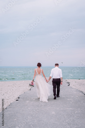 Wedding couple walking on the sand beach.