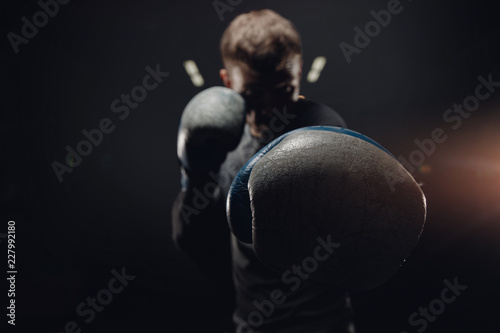 Portrait muay thai silhouette boxer man in gloves against dark background. Concept training boxing. © Parilov