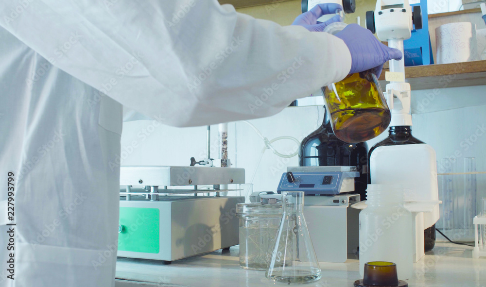 Chemical analysis laboratory. Close up hands of the scientist chemist dropping a indicator to flasks with a solution. Chemical analysis laboratory. Close up hands of the scientist chemist dropping a indicator to flasks with a solution.