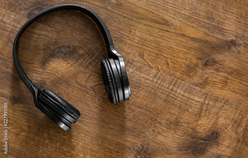 wireless Black headphones on wooden table background with copy space. top view