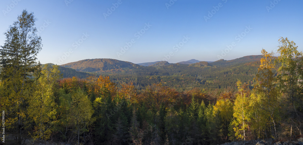Panoramic view from Klic or Kleis one of the most attractive view-points of the Lusatian Mountains with autumn colored deciduous and coniferous tree forest and green hills, golden hour light.