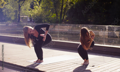 Yoga. Two attractive woman doing yoga exersices in the park. Summer morning photo