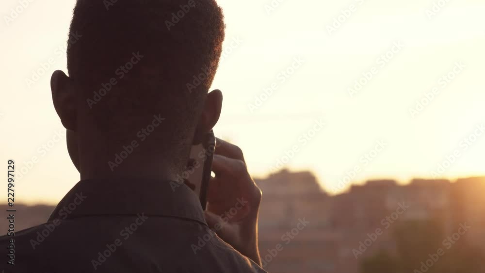Black american man talking by phone looking the city- back view