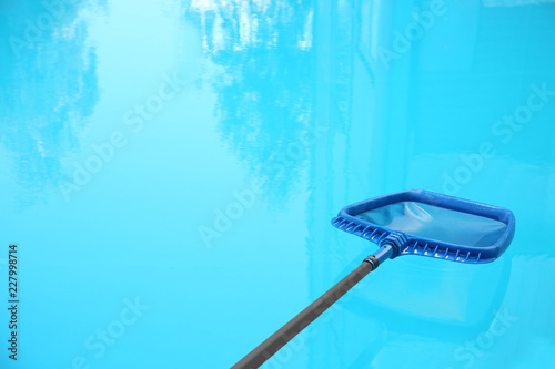 Cleaning outdoor pool with scoop net, closeup