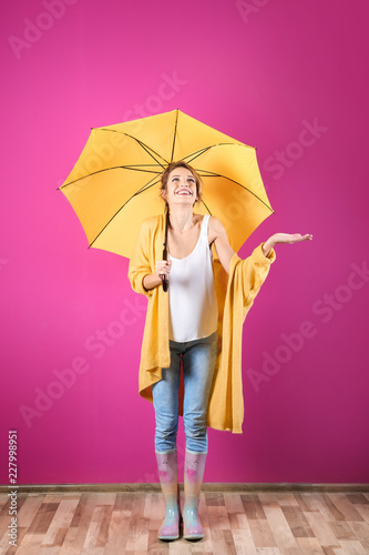 Woman with yellow umbrella near color wall