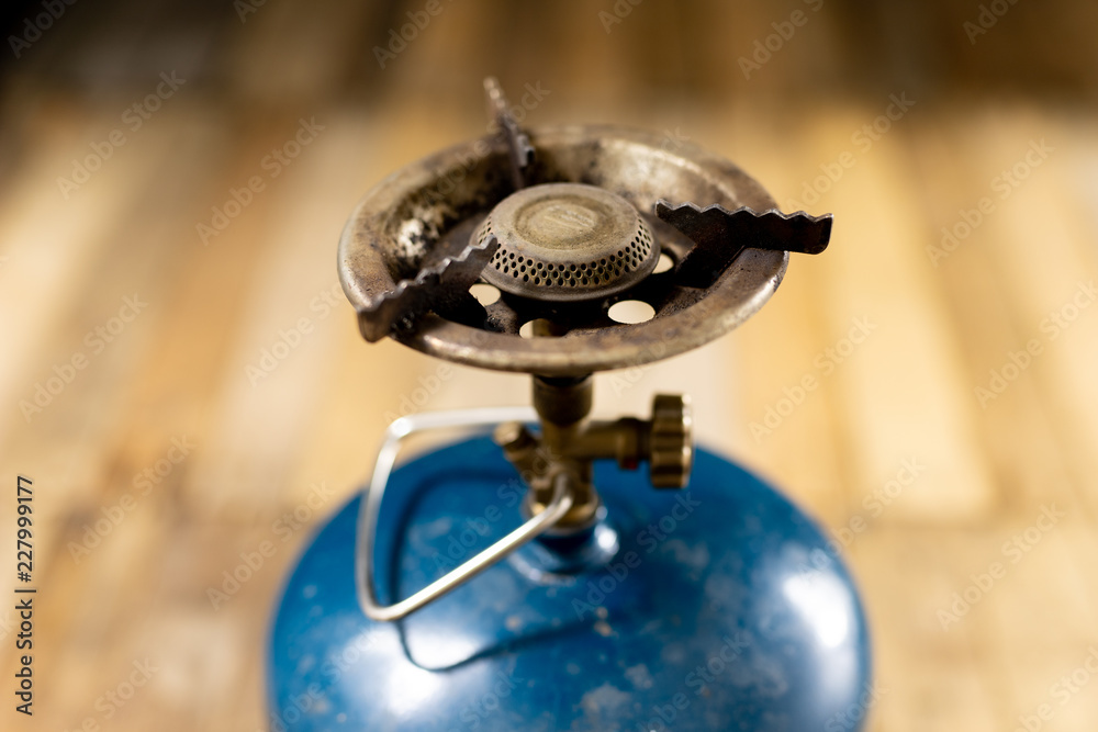 An old gas burner for preparing dishes. Tourist accessories on an old wooden table. An old gas burner for preparing dishes. Tourist accessories on an old wooden table.