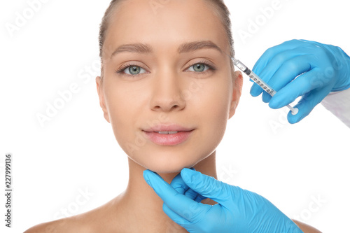 Young woman getting facial injection on white background. Cosmetic surgery concept