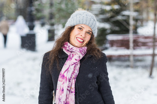 City, fashion and winter concept - Beautiful happy woman dressed in black coat, pink scarf and grey hat