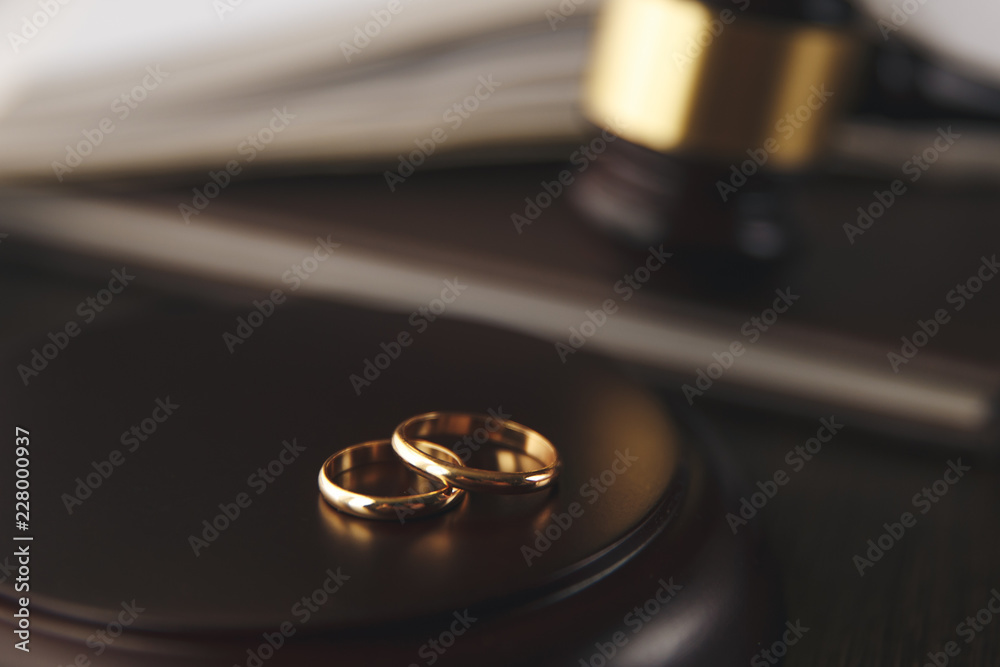 Closeup of wedding rings on wooden mallet at table in courtroom