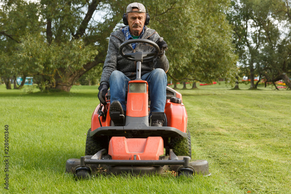 lawn mower tractor working in the town park lawn mower tractor working in the town park