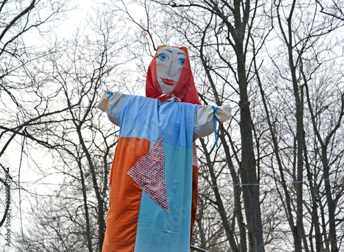 Foto Maslenitsa effigy with the drawn person against the background of trees