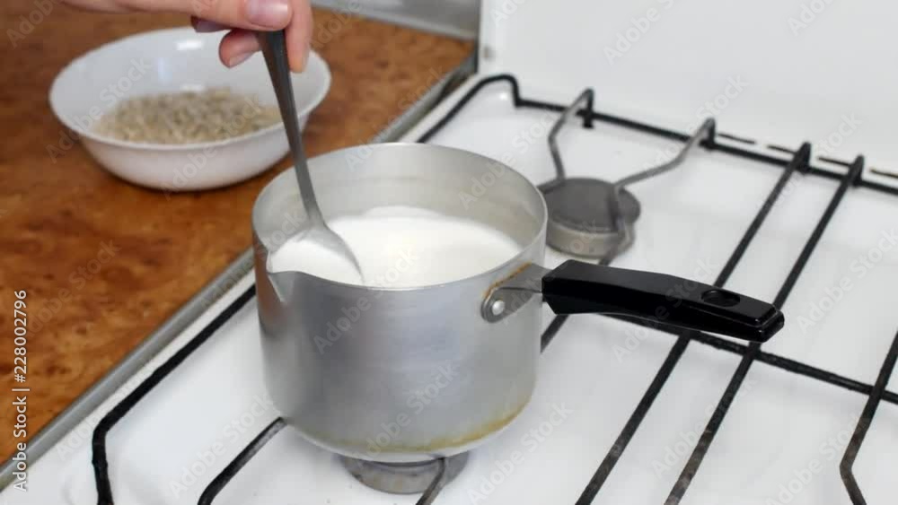 Cooking oatmeal, boiling milk and oatmeal in a plate, close-up, stir with a spoon, cereal Cooking oatmeal, boiling milk and oatmeal in a plate, close-up, stir with a spoon, cereal