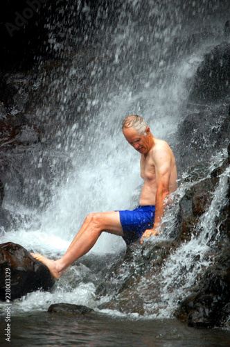 Brave Tourist Sits Under a Waterfall Kauai Hawaii