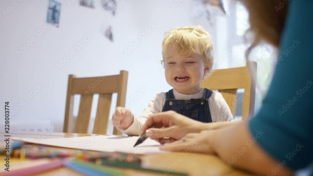Young toddler at the kitchen table drawing with his mother Young toddler at the kitchen table drawing with his mother