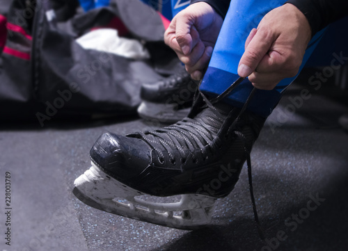 hands tying shoelaces of ice hockey skates in locker room