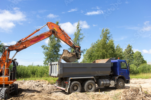 Fotografía The excavator loads the tipper truck on construction site