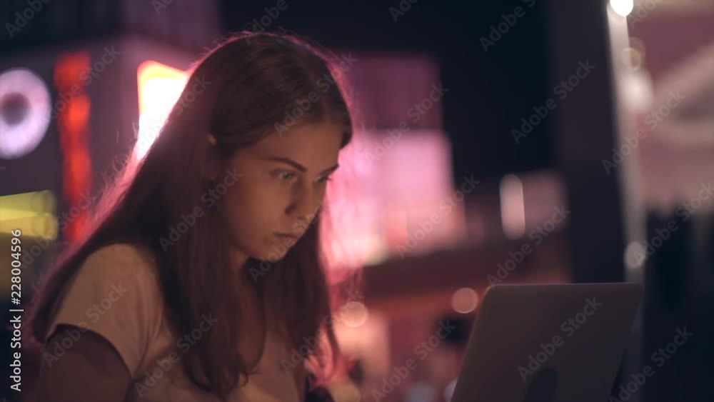 The girl works outside the office with a laptop in the night city The girl works outside the office with a laptop in the night city