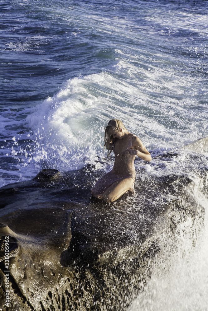 beautiful blond woman on rocks by the ocean