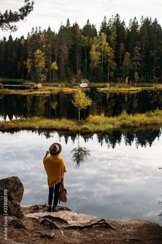 Woman in a yellow poncho and hat in the autumn time in national park Nuuksio, Finland