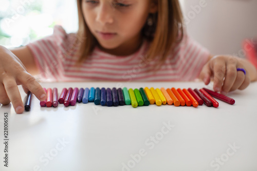 A child lines up colorful crayons in a row.  photo