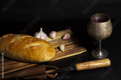 cup of wine with bread, vegetables on dark background
