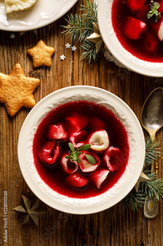 Christmas beetroot soup, borscht with small dumplings with mushroom filling in a ceramic bowl on a wooden table.  Traditional Christmas eve dish in Poland. 