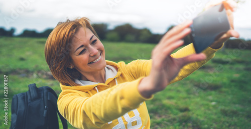 tourist girl on background green grass taking photo selfie on mobile smart phone, person looking on camera gadget technology, blogger using content online wifi internet lifestyle concept