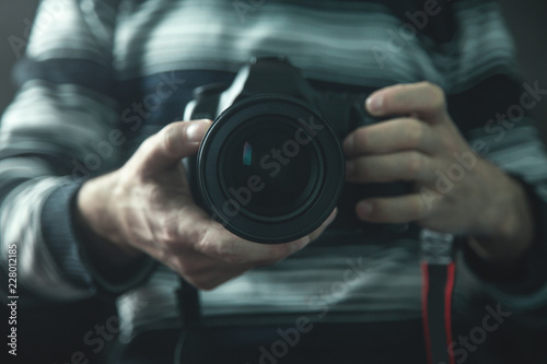 Professional photographer holding a DSLR camera.