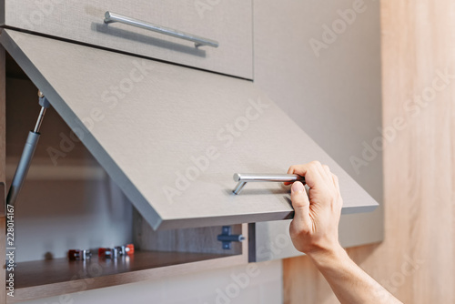man hand open kitchen cupboard with handle photo