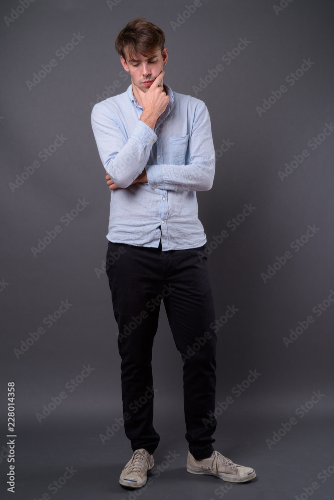 Studio shot of young handsome man against gray background