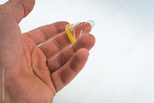 Close-up of a condom in his hand. Contraceptive protection against pregnancy, AIDS.