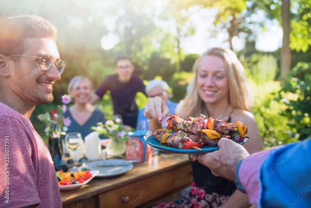cheerful family gathered around a table for a bbq in the garden cheerful family gathered around a table for a bbq in the garden