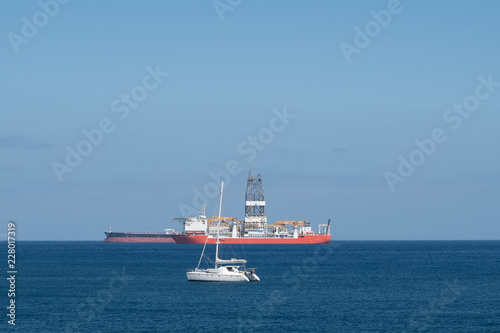 sailing boat, drilling ship and tanker on ocean horizon  
