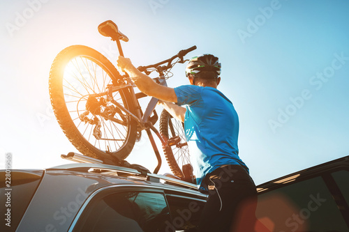 Mountain biker man take of his bike fron the car roof