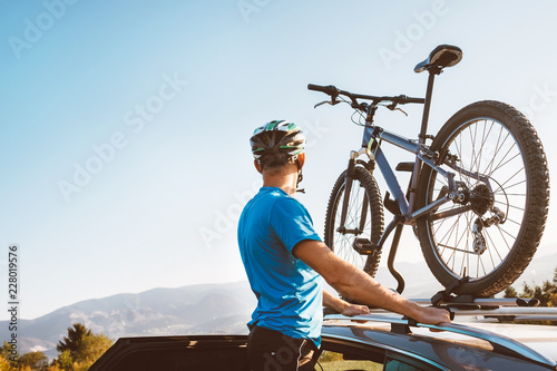 Man take his bicycle from car roof