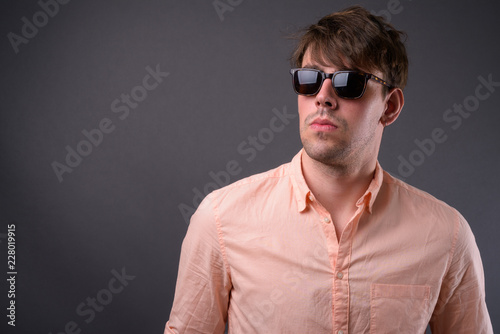 Portrait of young handsome businessman against gray background © Ranta Images