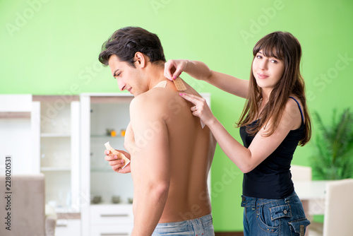 Wife applying pepper Capsicum plaster to husband to relieve pain