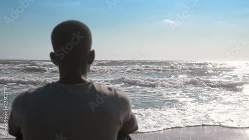 Missing homeland,refugee. Young black migrant alone obesrving the sea photo