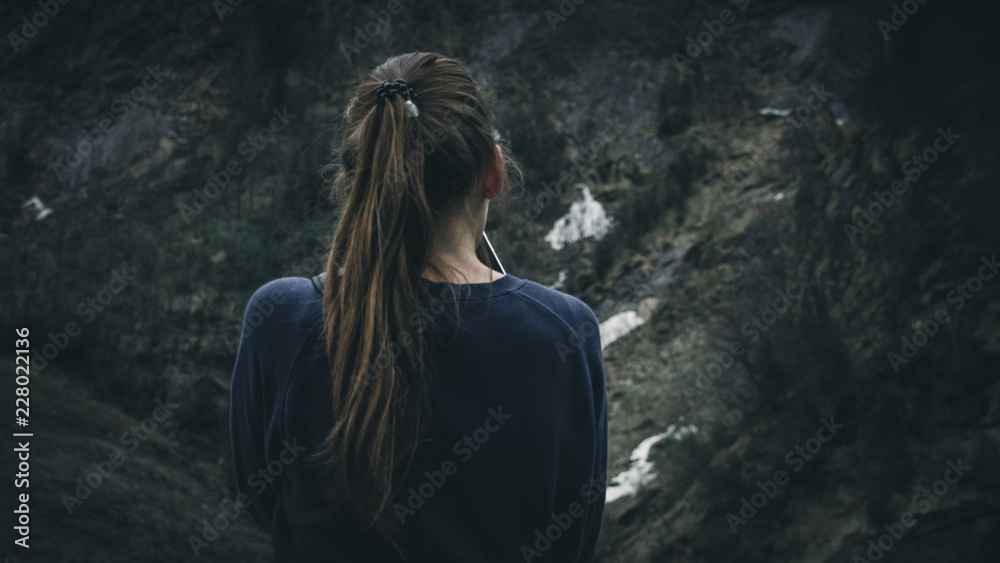 Frau schaut auf eine Felswand. Die Bildstimmung ist bedrückend und depressiv.