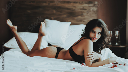 Woman Lies on Bed in Black Lingerie and Stockings.