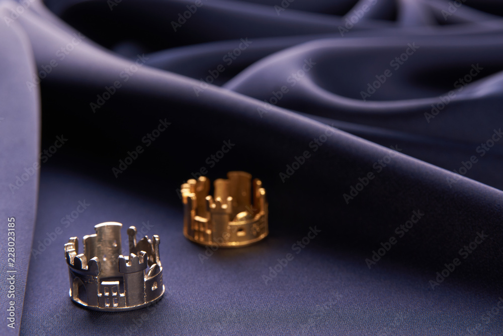 Gold and silver ring in the shape of a castle on blue silk background, with copy space. Beautiful precious women's jewelry, close-up Gold and silver ring in the shape of a castle on blue silk background, with copy space. Beautiful precious women's jewelry, close-up