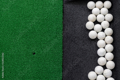 Golf balls on a synthetic grass mat at a practice range.