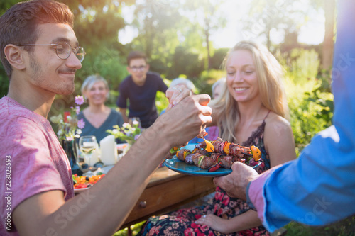 cheerful family gathered around a table for a bbq in the garden photo