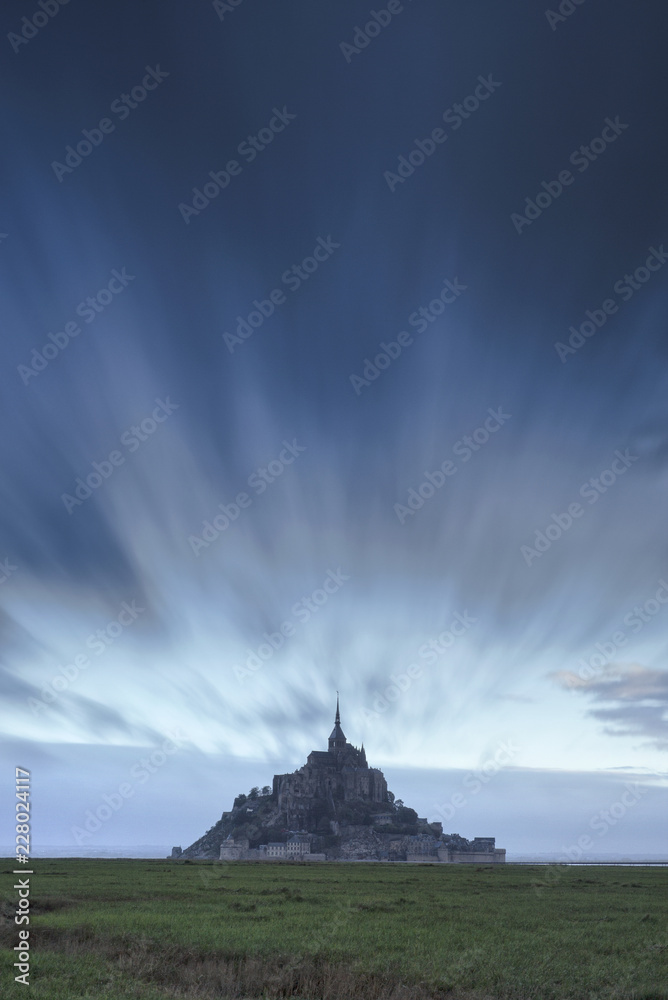 blurred clouds in dark blue sky above old castle in Normandy in France