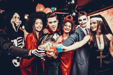 Friends in Halloween Costumes Drinking Cocktails