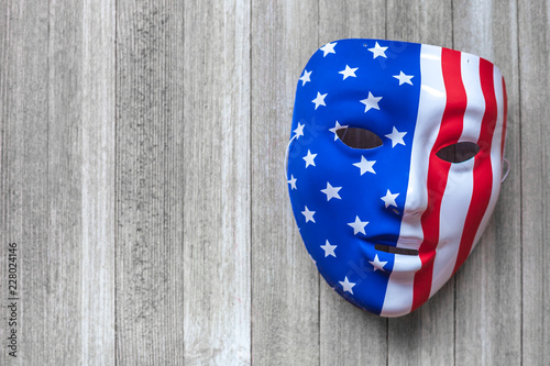 Mask with american flag painted over on a wooden background. Conspiracy theory concept photo