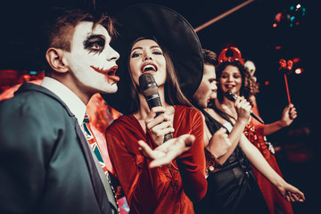 Young People in Halloween Costumes Singing Karaoke