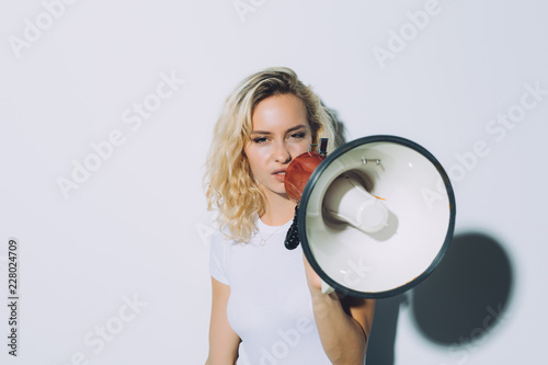 Young blonde girl shouting by megaphone isolated on white background